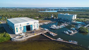 Un port de plaisance avec des bateaux amarrés, un grand bâtiment doté d’un garage et un hôtel à plusieurs étages.