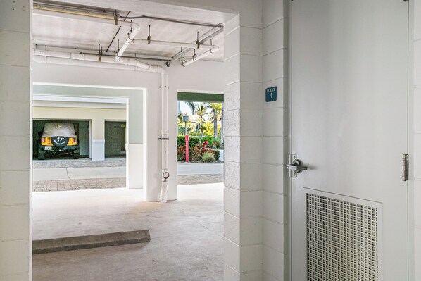 A clean, modern entrance with a concrete floor, a metal door with a vent, and a view of a parking area with a yellow vehicle. - Penthouse View at One Particular Harbour 388-401 · Top Floor · Pool Lanai (Bradenton)