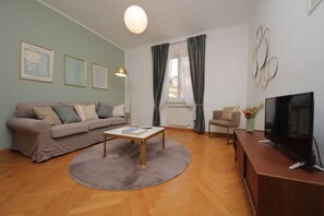 A living room with a sofa, a coffee table, a TV, and a lamp. - Comodo appartamento con due stanza al Colosseo (Roma)