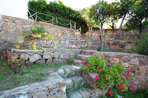 A stone staircase with a garden area, surrounded by greenery and a white building. - Dimora Burrafato, known by locals as “La Casa Rossa”, is a historic summer residence once owned by Princess Pignatelli, located directly on the seafront of Caronia. The property consists of three independent units, each with a private entrance, a bal (Marina di Caronia)
