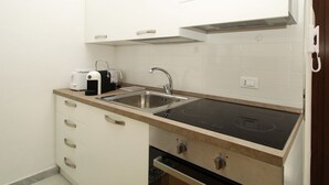 Una cocina compacta con un lavamanos doble, estufa empotrada y muebles blancos.
