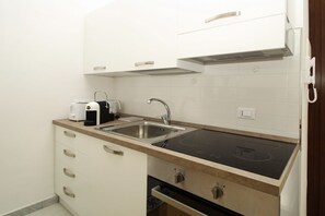 A compact kitchen with a double sink, a built-in stove, and white cabinetry. - Dimora Burrafato, known by locals as “La Casa Rossa”, is a historic summer residence once owned by Princess Pignatelli, located directly on the seafront of Caronia. The property consists of three independent units, each with a private entrance, a bal (Marina di Caronia)