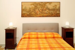A bedroom with a bed, two nightstands, and a painting on the wall. - Dimora Burrafato, known by locals as “La Casa Rossa”, is a historic summer residence once owned by Princess Pignatelli, located directly on the seafront of Caronia. The property consists of three independent units, each with a private entrance, a bal (Marina di Caronia)