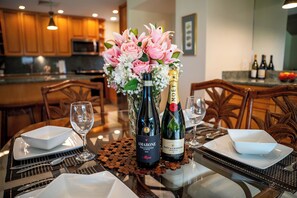 Ein Esstisch ist gedeckt mit einer Flasche Amarone-Wein, einer Flasche Moet & Chandon-Champagner und einem Strauß rosa Blumen.