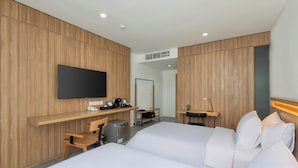 Een hotelkamer met een bed, een bureau met een computer, een televisie en een kleine kitchenette.