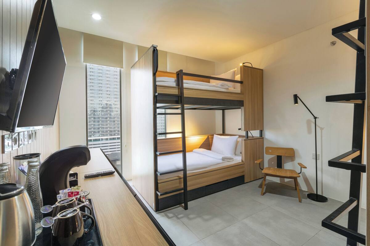 A bunk bed room with a desk, chair, and a TV.