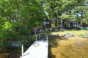 A cabin with a dock extending into a river, surrounded by trees. - New for 2026! Thomas Pond Cottage with Sandy Beach, Firepit & Lake Views (Raymond)
