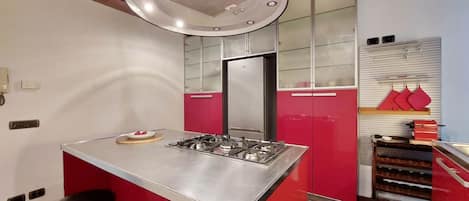 Una cocina moderna con una isla central, armarios rojos y una estufa de acero inoxidable.