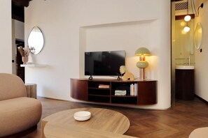 Ein modernes Wohnzimmer mit Flachbildfernseher, Couchtisch aus Holz und Bücherregal.