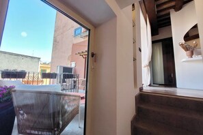 Ein Balkon mit Korbmöbeln, einem Blumentopf und Blick auf die Nachbargebäude.