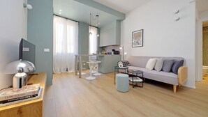 En moderne stue med sofa, sofabord og et spiseområde med bord og stole.