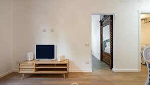 A room with a wooden entertainment unit, a large mirror, and a bed with a wooden headboard. - Cami’s Corner - Heart of Cagliari (Cagliari)