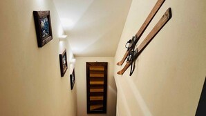 A narrow hallway with wooden flooring, a wooden door at the end, and skis mounted on the wall. - GuestHost - Charming 70 sqm apartment on two levels, comfortably accommodating four people.The property is located in La Salle, in the hamlet of Cottin, surrounded by Alpine nature at the foot of Mont Blanc, an ideal location for skiers and outdoor sport (La Salle)