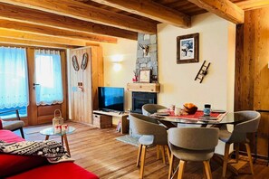Una sala de estar acogedora con chimenea, televisor y comedor con sillas y una mesa.