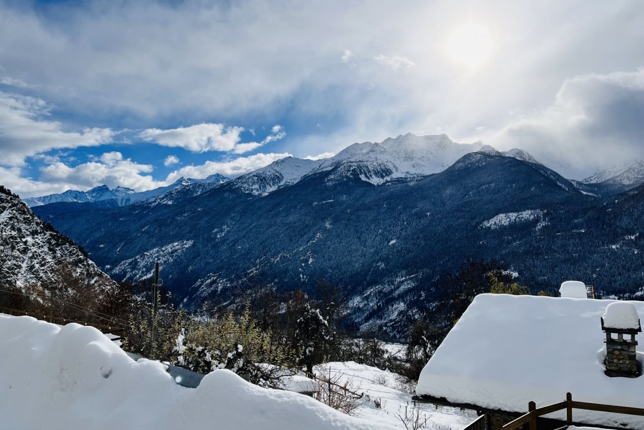 Eine Berglandschaft mit schneebedeckten Gipfeln und einer Holzhütte im Vordergrund.