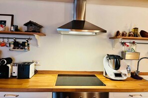 A kitchen with a stainless steel range hood, a built-in oven, a coffee maker, and a toaster.