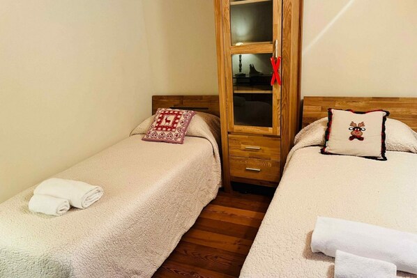 Un dormitorio con dos camas, un armario de madera y una mesita de noche.