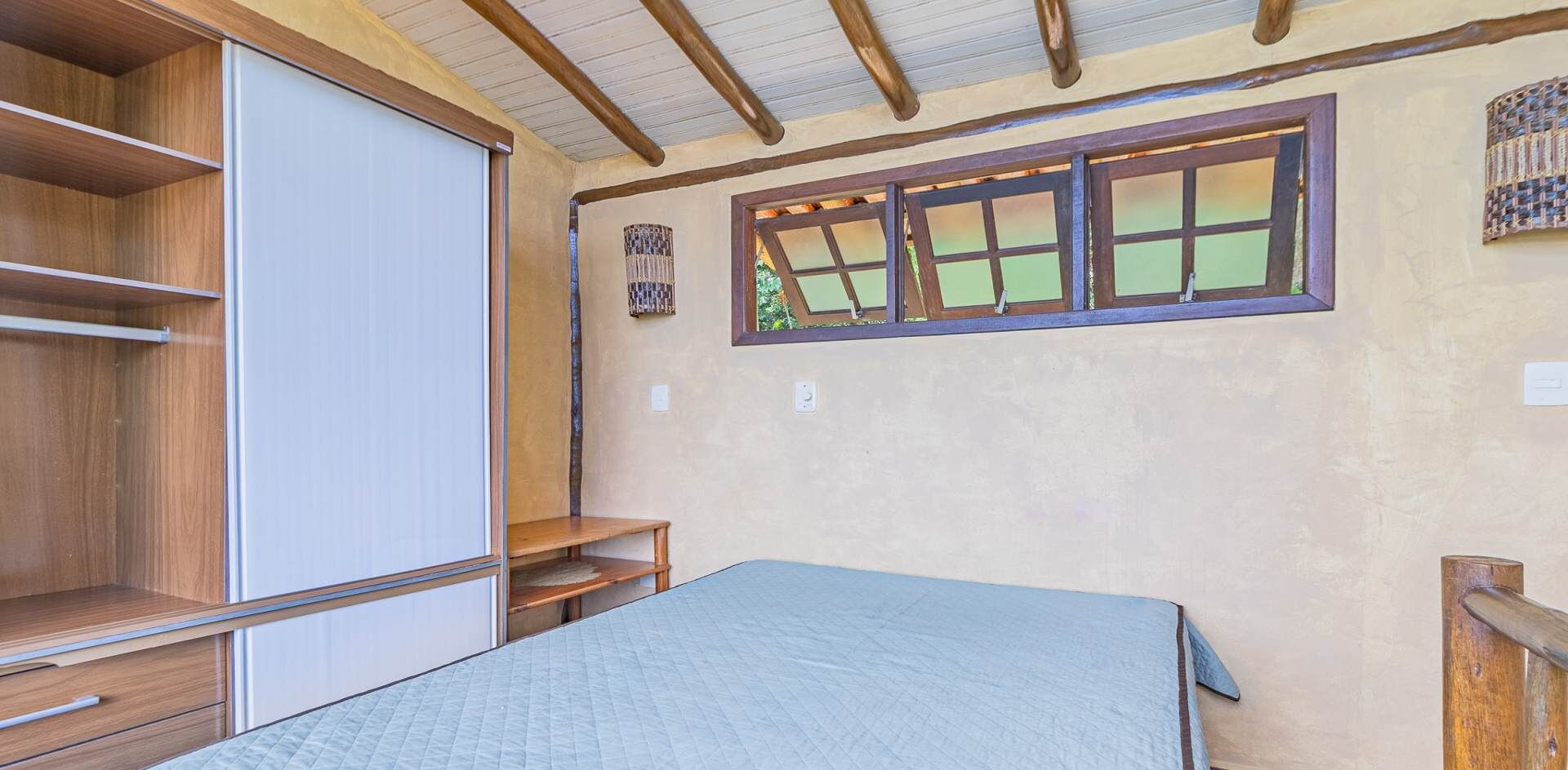 Un dormitorio con cama, estantes de madera, un armario y ventana con vistas.