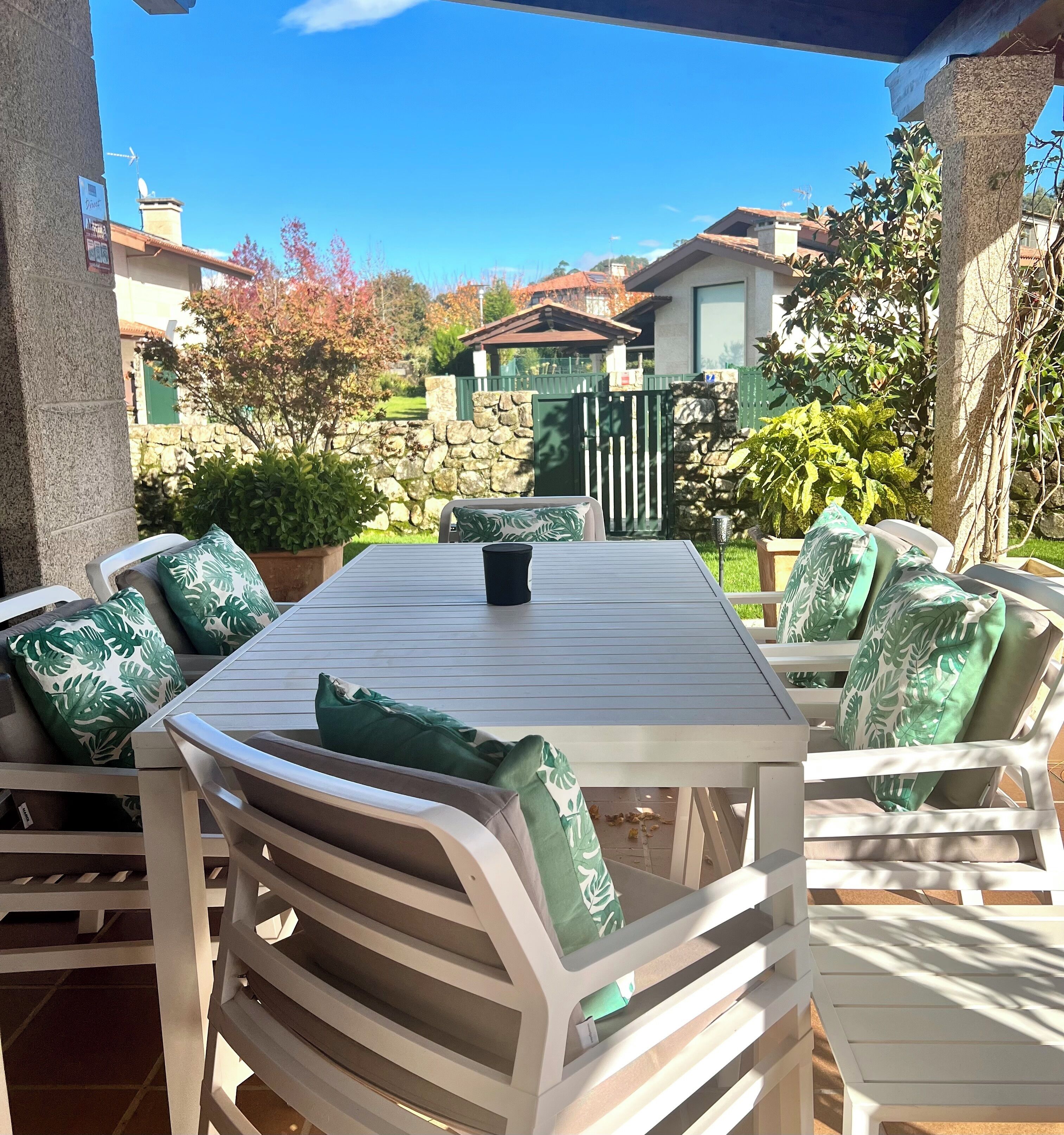 An outdoor patio with a table and chairs, stone walls, and a view of a residential area.