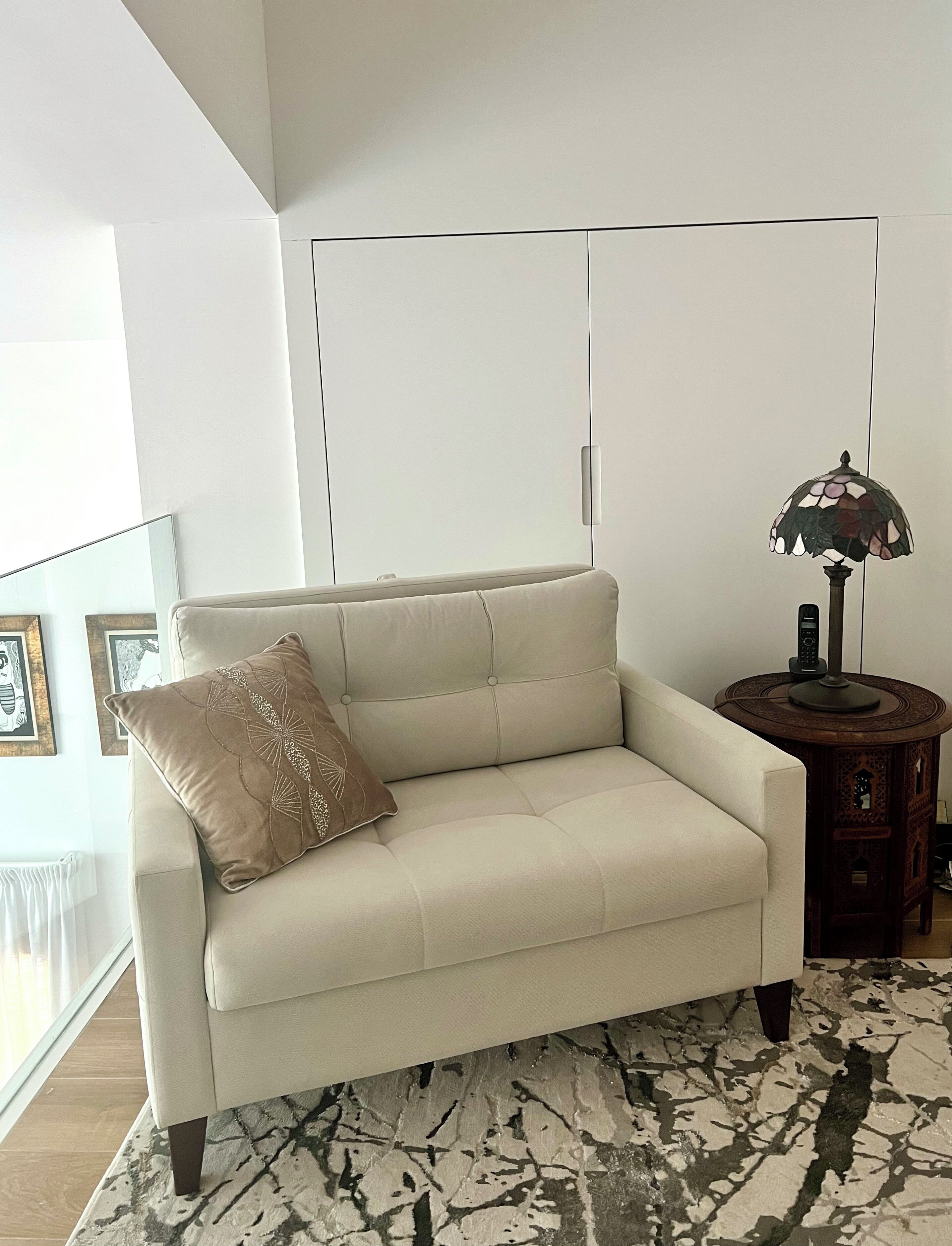 A modern living room with a sofa, a patterned rug, a lamp, and a side table.