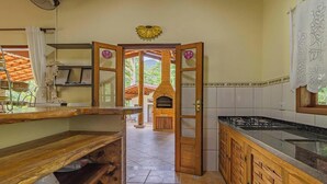 A kitchen with wooden cabinets, a gas stove, and a view of the outside. - Casa em Ubatuba a 10 minutos de carro da praia (Ubatuba)