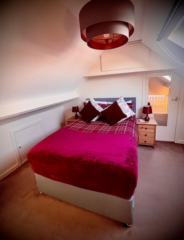 A bedroom with a bed, bedside tables, a mirror, and a window.