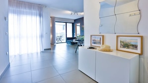 Una habitación de hotel moderna con un ventanal grande, un área de comedor y un espejo fijado a la pared.