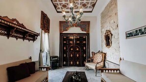 Una habitación tradicional con sofá, una silla, una mesita de centro, una araña y una puerta decorativa.
