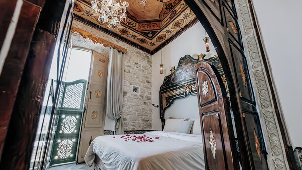 Un dormitorio con una cama grande, cabecera de madera, pared de piedra y candelabro.