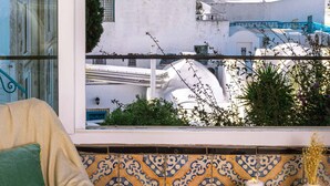 A balcony with a view of the sea and white buildings, a beige sofa, and a patterned tile backsplash. - Maison L'étoile de Sidi Bou Saïd - 360° Sea View (Sidi Bou Said)