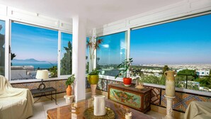 A balcony with a view of the city and sea, furnished with a table, chairs, and potted plants. - Maison L'étoile de Sidi Bou Saïd - 360° Sea View (Sidi Bou Said)