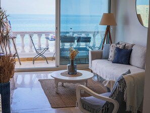 Ein Wohnzimmer mit Meerblick, ein weißes Sofa, ein Couchtisch und eine Lampe.