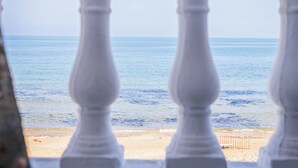 Une vue à travers une balustrade donnant sur une plage aux eaux calmes et au rivage sablonneux.