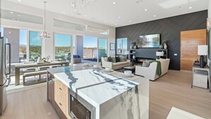 Un'ampia zona giorno con una grande isola in marmo, una cucina moderna e una sala da pranzo con vista sull'esterno.