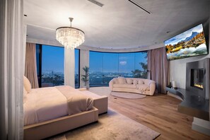 Un dormitorio moderno con una cama grande, un sofá, un televisor y una chimenea.