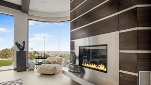 Ein modernes Wohnzimmer mit Kamin, großem Fenster und Blick auf die Stadt.