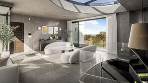 Ein modernes Interieur mit gewölbter Decke, einer Glasstiege und einem großen Fenster mit Blick ins Freie.