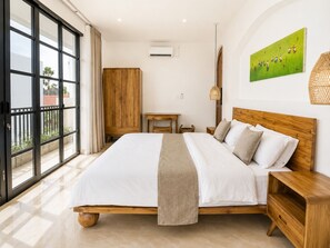 A bedroom with a large bed, a wooden wardrobe, a small table, and a painting on the wall. - 3BR Private Pool Villa in Berawa • Walk to Beach, Cafes & Finns (Bali)
