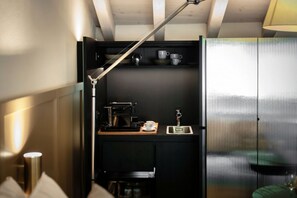 A compact kitchenette with a coffee maker, a sink, and a shelf with cups. - HH - Suite Diletta - MyHomeinComo (Argegno)