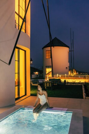 A person sitting by a pool with a house in the background.