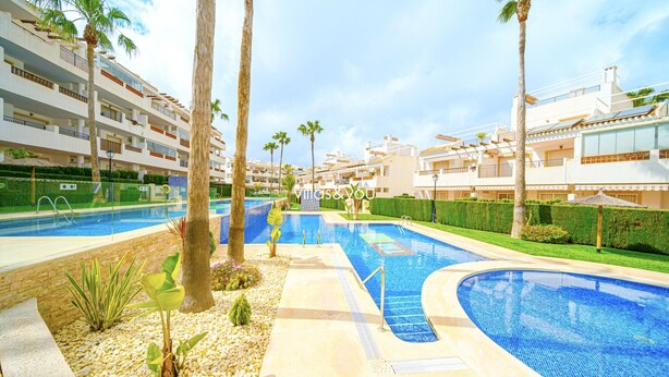 A resort with multiple swimming pools, palm trees, and a modern building with balconies. - Linnea Sol by Villas&You (Orihuela Costa)
