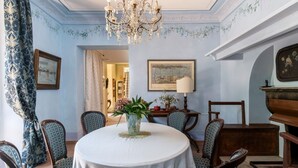 A dining room with a round table, chairs, a chandelier, and wall art. - Pink Villa - MyHomeinComo (Carate Urio)