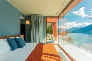 Une chambre d’hôtel moderne dotée d’un grand lit, offrant une vue sur les montagnes et comprenant un balcon avec des portes vitrées.