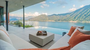 Ein moderner Außenbereich mit Sitzgelegenheit und Blick auf einen See und Berge.