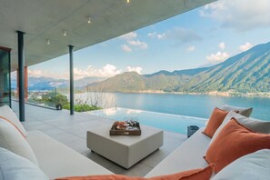 A modern outdoor seating area with a view of a lake and mountains. - Villa Aurea - My Home in Como (Sala Comacina)