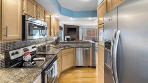 A modern kitchen with wooden cabinets, stainless steel appliances, and a tiled backsplash. - Premiere Pointe Golf Discounts (Branson)