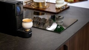 Een keukenblad met een koffieapparaat, een mokkenhouder en een decoratieve vaas met bloemen.