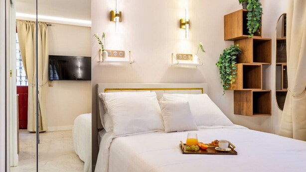 Een hotelkamer met een bed, nachtkastjes, een televisie en een ontbijtbakje.