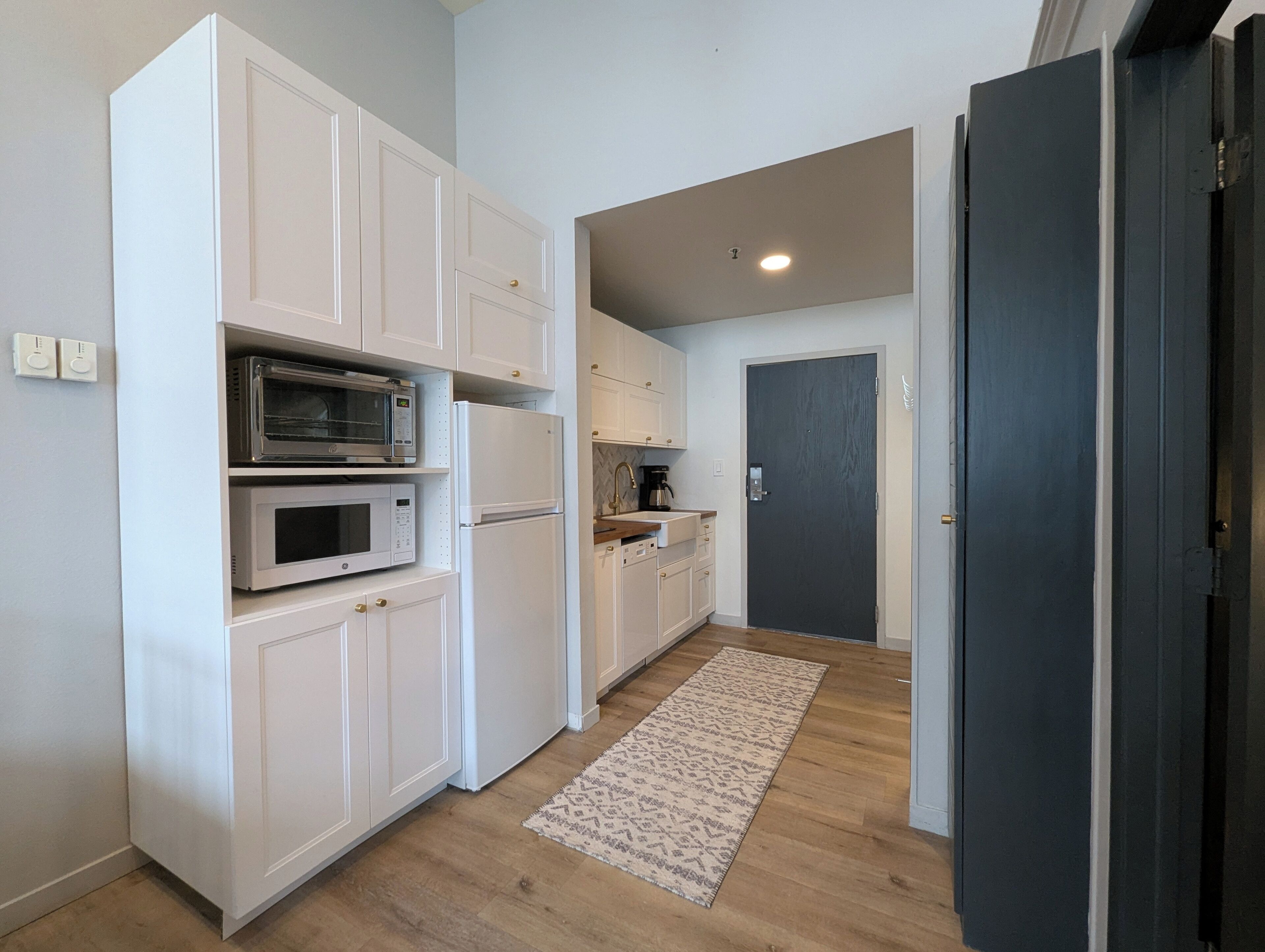 A modern kitchen with white cabinetry, a microwave, and a refrigerator.