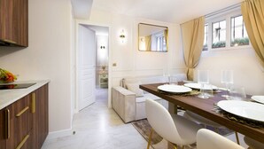 Un espace repas moderne avec une table en bois dressée pour quatre personnes, des chaises blanches et une vue sur l’extérieur grâce à de grandes fenêtres.